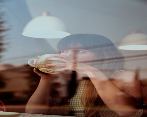 Woman drinking coffee while reading in a sunny cafe in Roma Norte, Mexico City